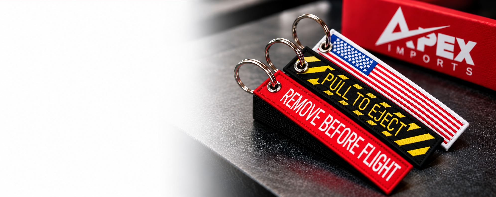 Embroidered keychains beside an Apex Imports box